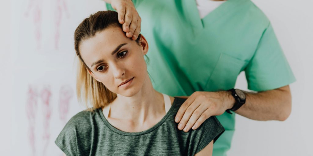 Chiropractor performing neck adjustment on female patient